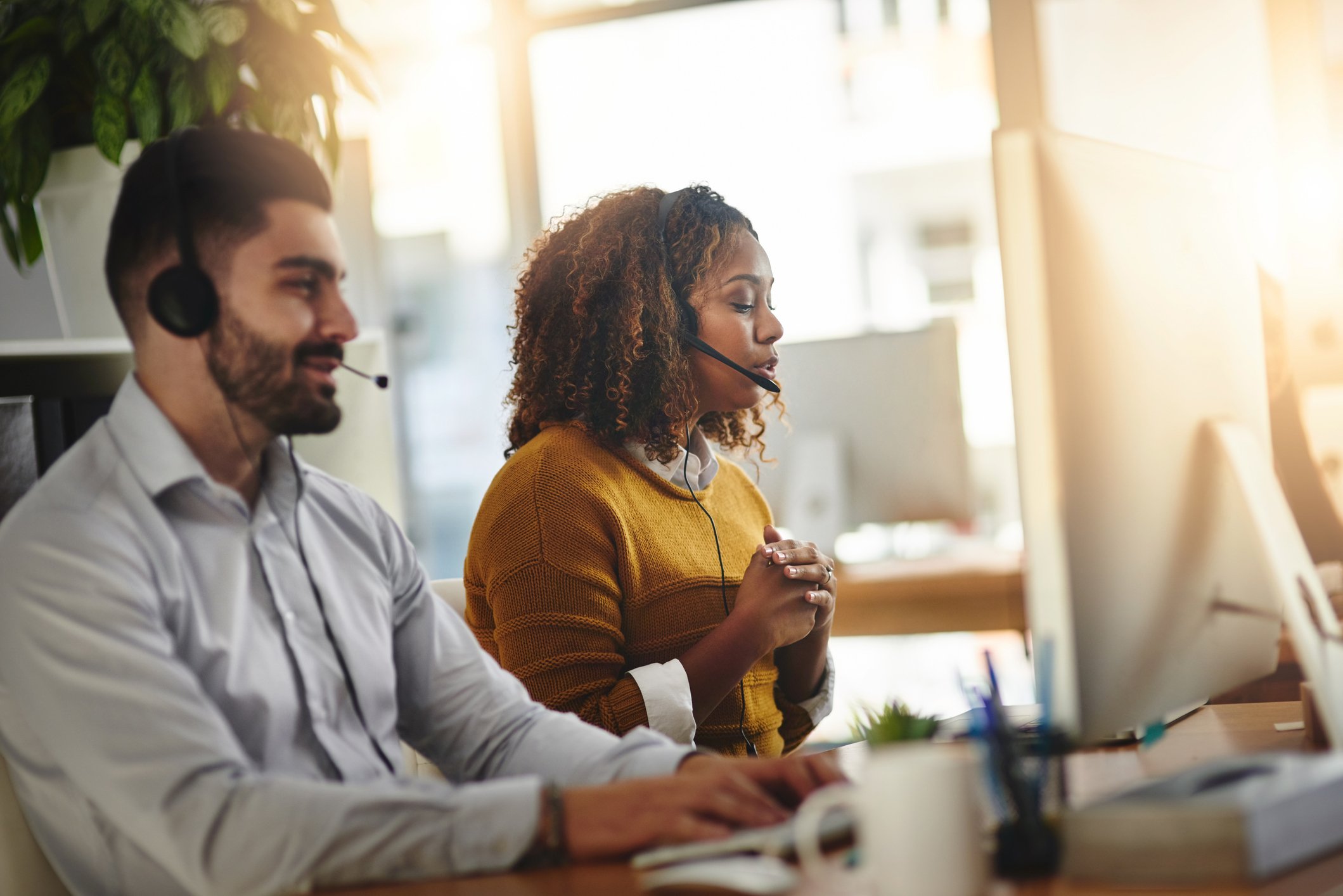 Two support agents speaking with customers at their desks