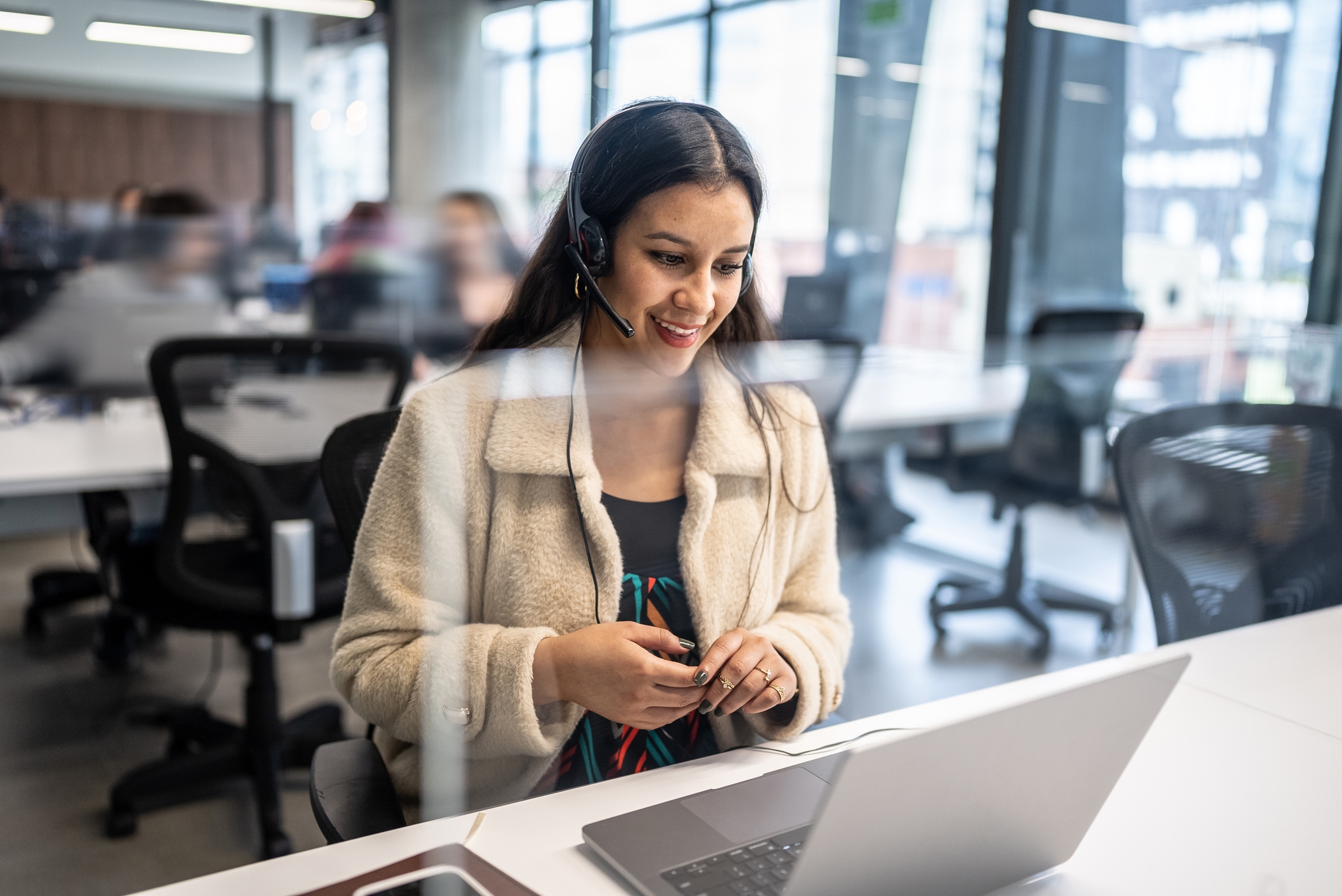 A woman wearing a headset while working at a computer in an office