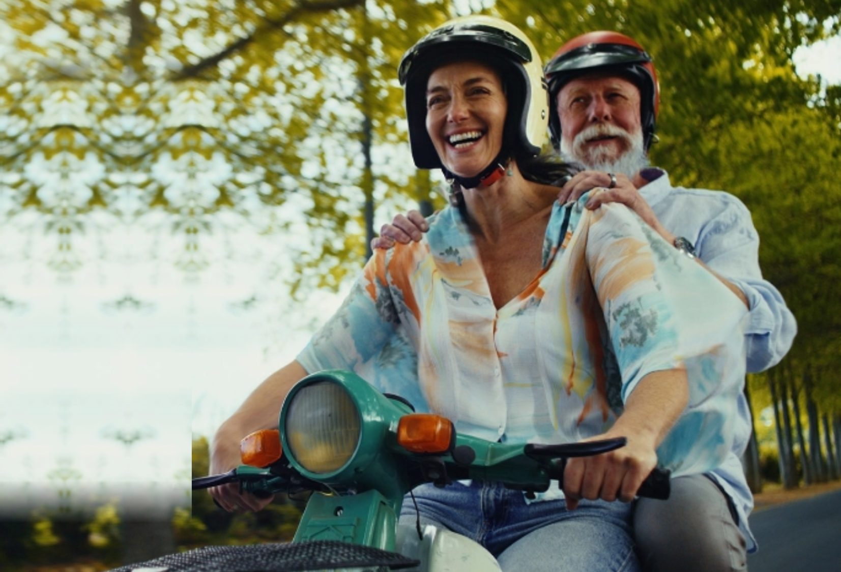 Couple riding a scooter on a tree-lined road, from the Staysure customer story
